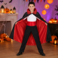 Preview: Kind mit schwarz-rotem Vampir-Umhang, Schärpe und Spinnennetz-Kragen in einer Halloween-Kulisse