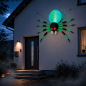 Preview: Beleuchtete Halloween-Spinne mit grünem Hinterleib und roten Augen an einer Hausfassade