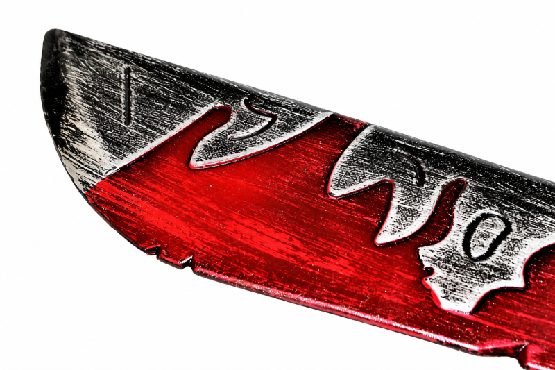 Detailaufnahme der grau-silberfarbenen Machetenklinge mit roten Bluteffekten und eingearbeiteten Symbolen